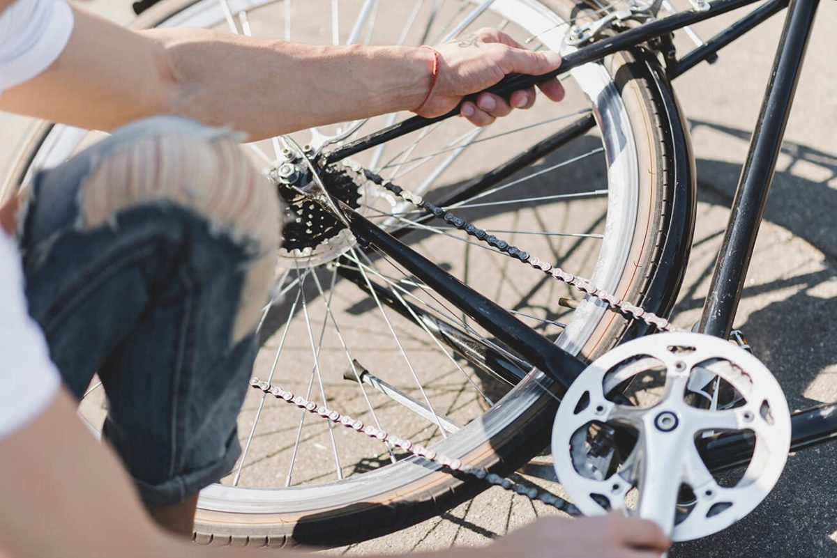 person putting a bike chain back on