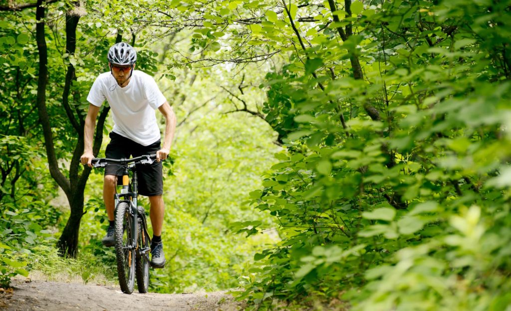 man riding moutain bike through forest