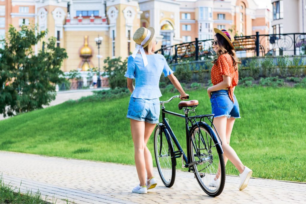 two female friends pushing bike