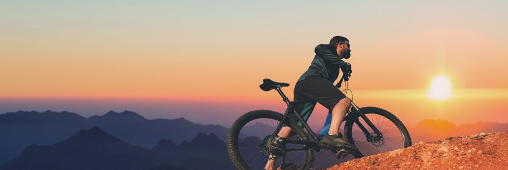 man pushing bike up a mountain
